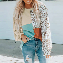 Woman wearing a leopard print sheer top over a colorful sweater and jeans.