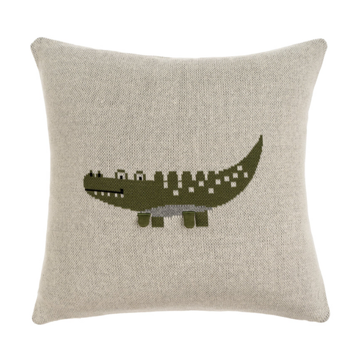 A knit pillow with a crocodile pattern in green and beige colors on a light background.