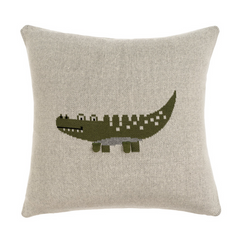 A knit pillow with a crocodile pattern in green and beige colors on a light background.