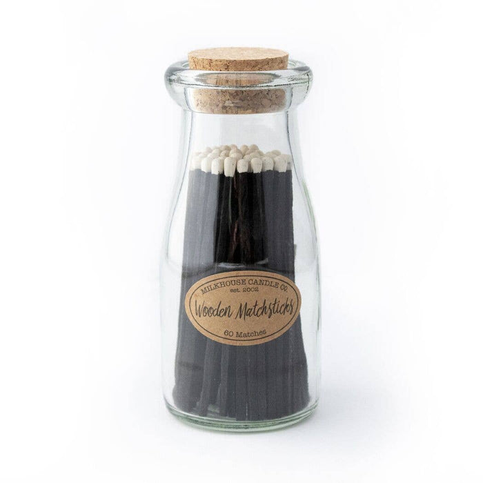 Glass bottle with cork lid containing wooden matchsticks on a white background