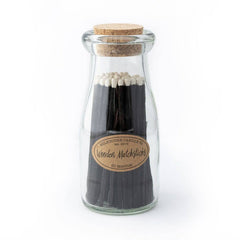 Glass bottle with cork lid containing wooden matchsticks on a white background