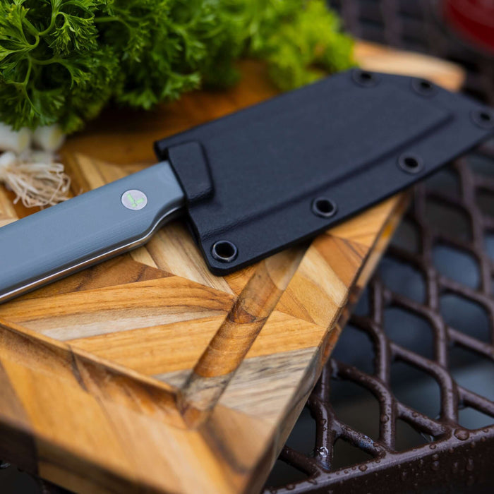 Leatherman Rustle in sheath placed on a cutting board alongside a selection of vibrant vegetables, indicating meal preparation.