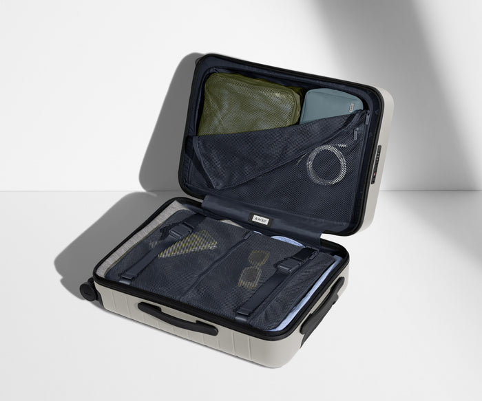 The Carry-On suitcase in Cloud Gray shown open on its side and packed with Away's packing organizers to show capacity and the interior compression system, designed to help you pack more in
// 
Our signature interior compression system allows you to stay more organized. Paired with The Insider Packing Cubes.